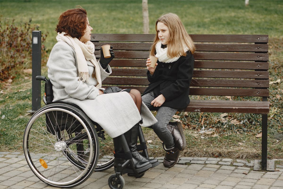 A participant chatting with a support worker on a park bench