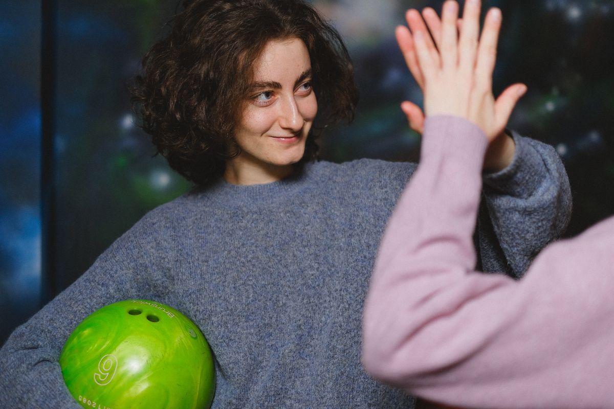 Friends sharing a high-five while bowling, representing social skills development